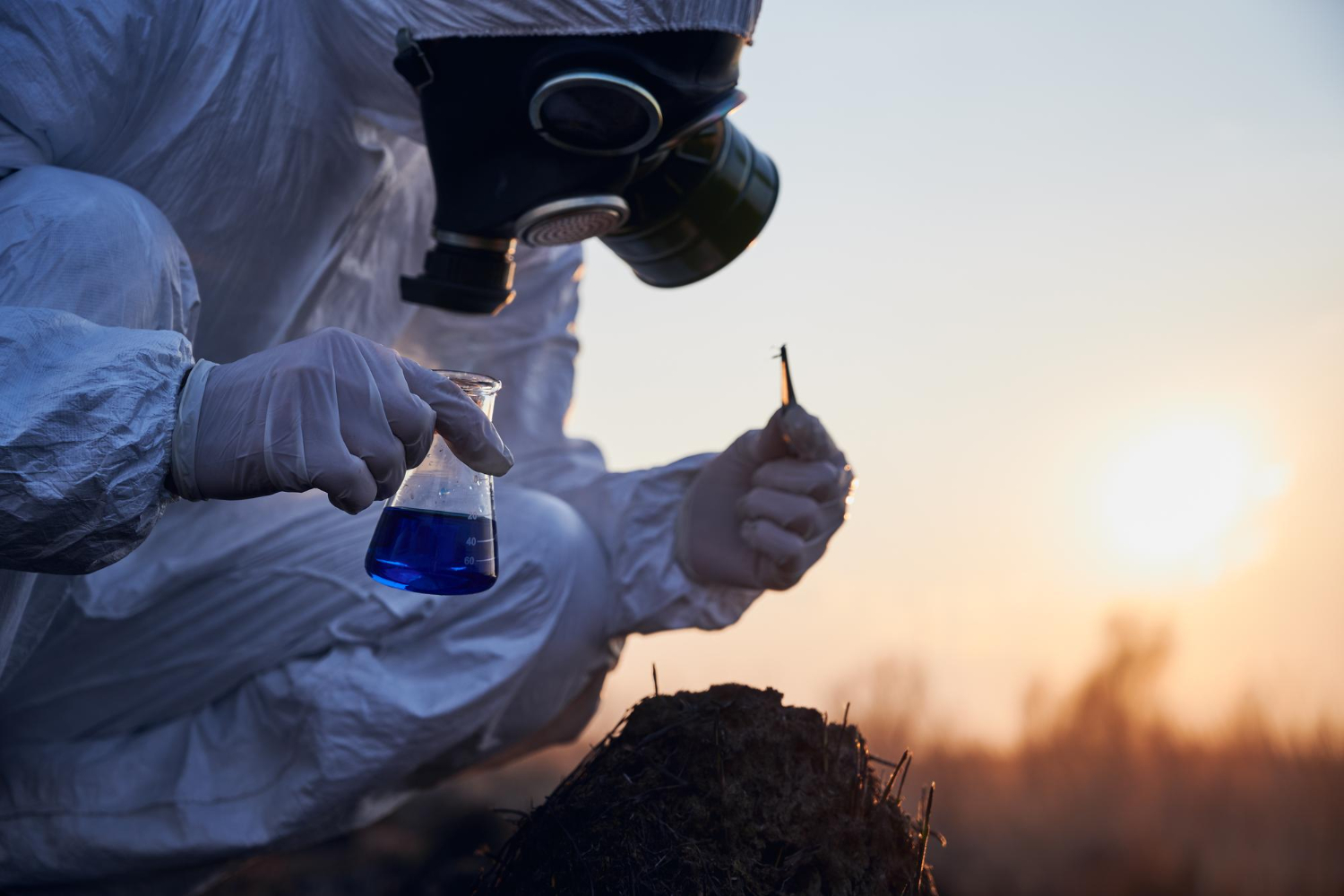 Guy in hazmat suit picking ground with plier